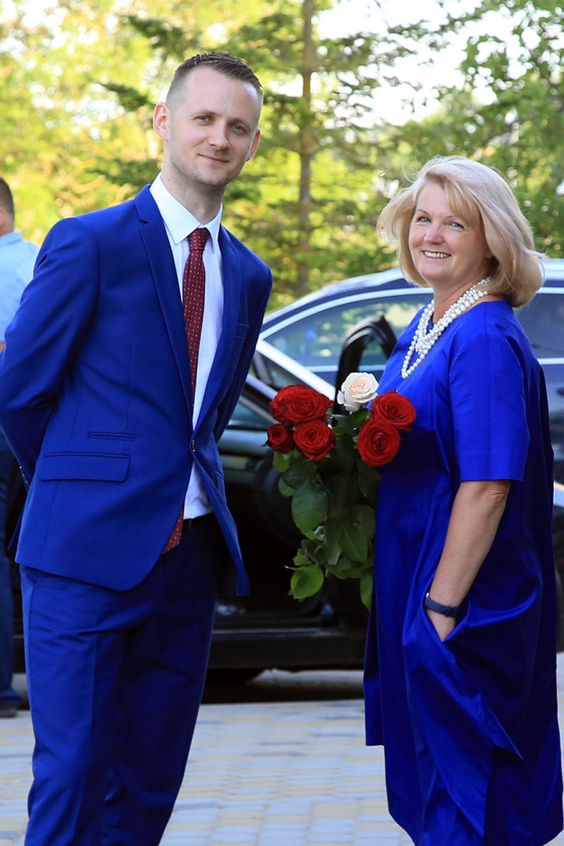 Vīrietis zilā uzvalkā un sieviete zilā kleitā